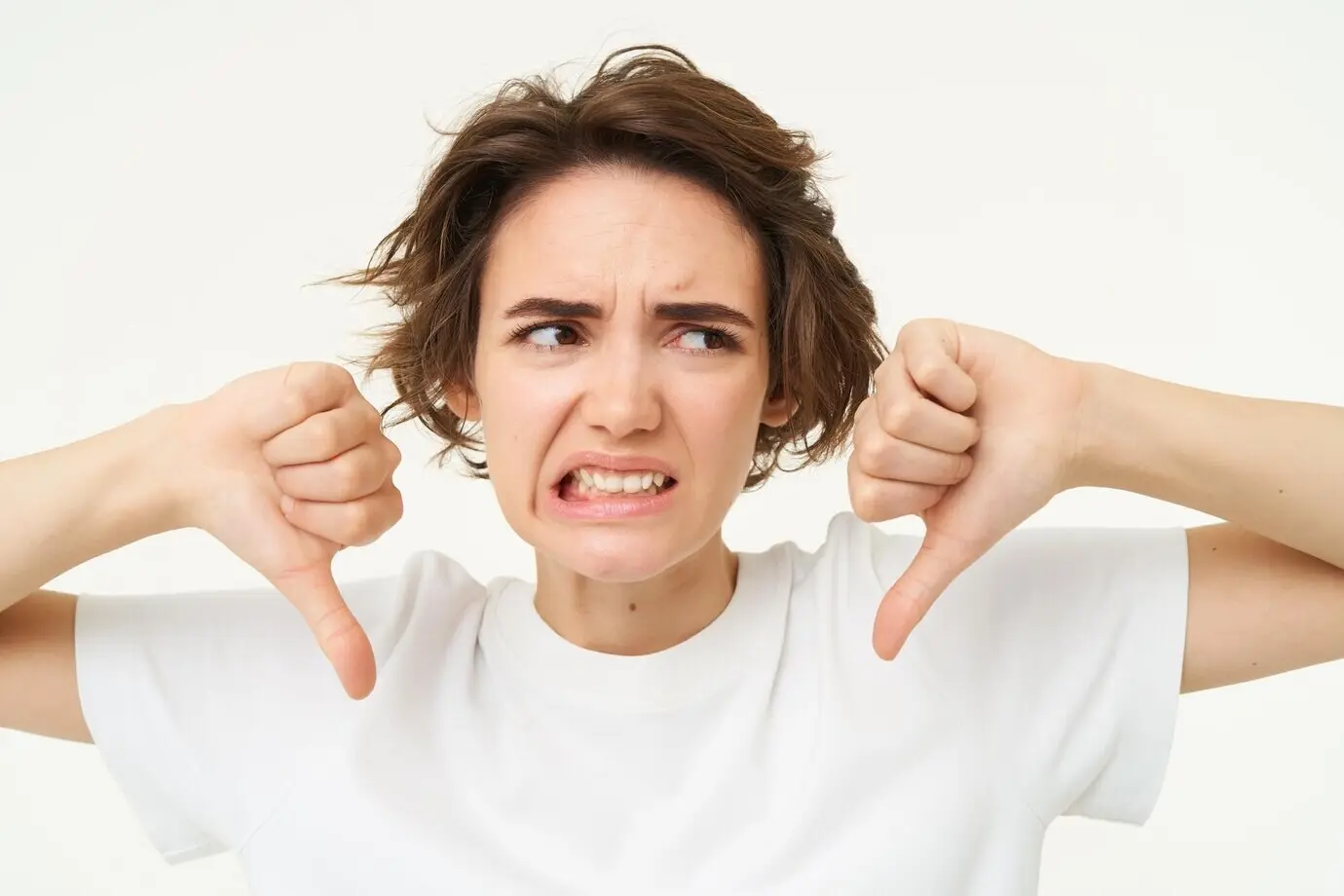 Nahaufnahme einer enttäuschten jungen Kundin, die mit einer Daumen-nach-unten-Geste ihre Ablehnung zeigt und das Gesicht verzieht.